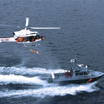 En sjöbevakningshelikopter och en sjöbevakninsbåt åker vid sidan om varandra.