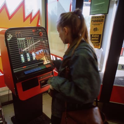 Kvinna spelar på penningautomatspel i ett snabbköp, 1990