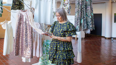 En kvinna i färggrann klänning vid hängande klänningar