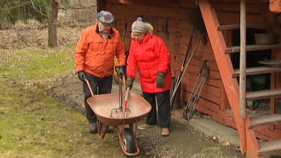 man och kvinna med skottkärra och krattor