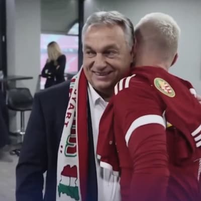 Viktor Orbán klädd i halsduk kramar en fotbollsspelare.
