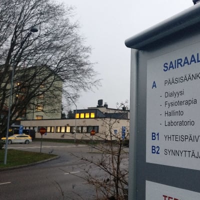 Oulaskankaan sairaalan opastekyltti, jonka takana näkyy sairaala.