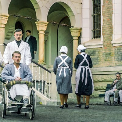 Hoitajat ja pyörätuolipotilas sairaalan pihalla sarjassa Charité (toinen tuotantokausi)