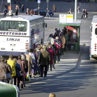 Ihmiset jonottavat paikallisliikenteen bussiin.