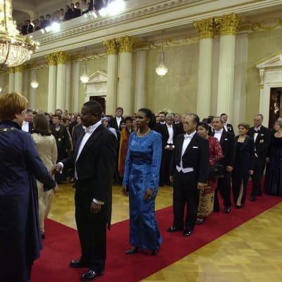 Diplomaterna anländer. President Tarja Halonen möter dem. Året är 2000.