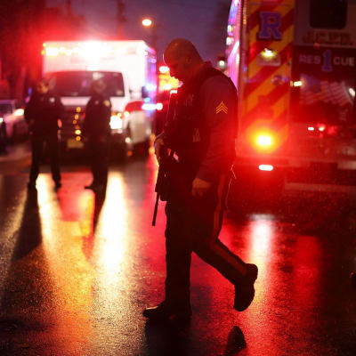 På bilden syns en polis i förgrunden och flera bakom honom gående på en mörk gata i Jersey City.