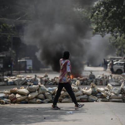Mielensosoittaja käveli savuavien barrikadien keskellä Yangonissa toissapäivänä.
