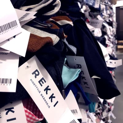 Rekki-verkkokaupan vaatteita hyllyssä ja niissä kaupan tuotelappu