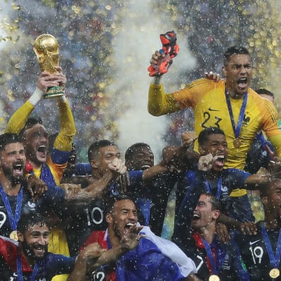 Ranskan miesten jalkapallomaajoukkue tuulettaa maailmanmestaruutta kaatosateessa ja konfettien keskellä.