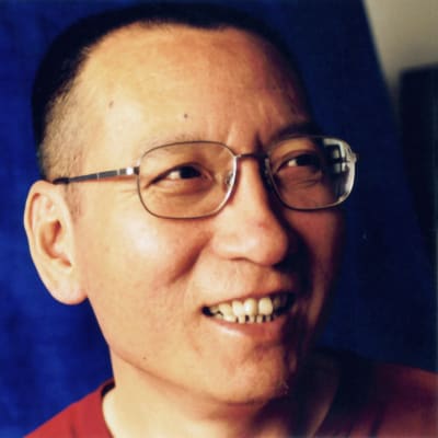 Liu Xiaobo hymyilee sinistä taustaa vasten.