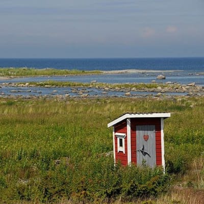 Bild från Kvarkens skärgård. Ett rött dass står i förgrunden.