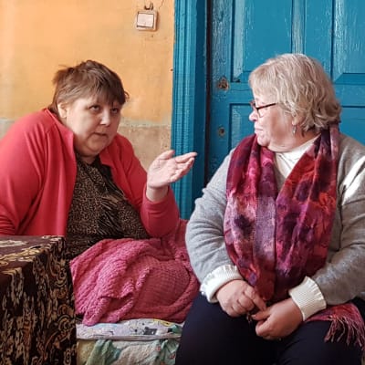 Frivilligarbetare talar med sjuk kvinna i säng