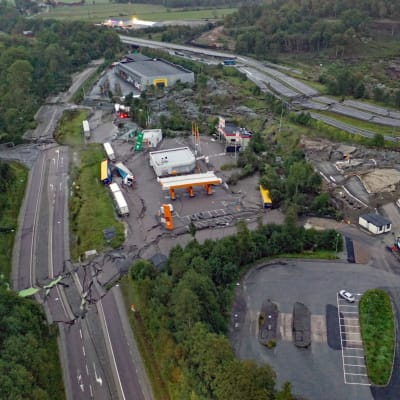 Bild tagen uppifrån på en motorväg som rasat samman. I bild syns flera lastbilar och byggnader samt skog i närheten av vägen.