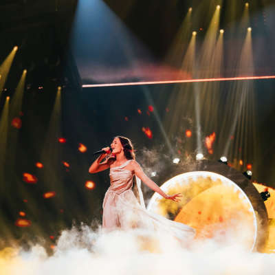 Eden Golan Euroviisuesityksen harjoituksissa lavalla. Laulajalla on valkoinen mekko. Taustalla valorengas.