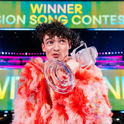 Nemo poseeraa lavalla lasisen mikrofoni pokaalin kanssa.