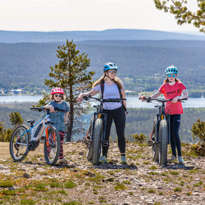Kirjailija Satu Rämö tyttäriensä kanssa Ylläksen maastossa polkupyörien kanssa.