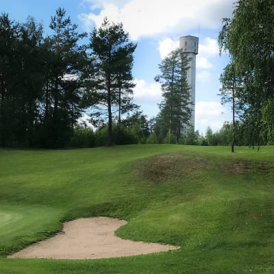etualalla golfkentän viheriö , hiekkakuoppa ja golflippu, taustalla Outokummun Keretin torni. 