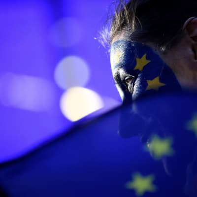 Nainen ja Euroopan lippu Euroopan parlamenttirakennuksen edessä vaali-iltana.