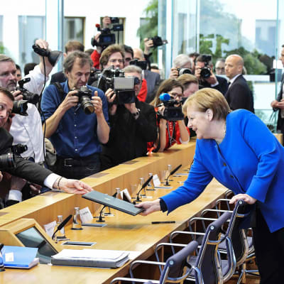 Saksan terveysministeri Jens Spahn ojentaa dokumentteja Angela Merkelille.