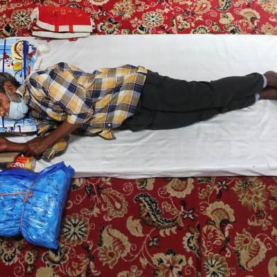Kuvassa mies makaa patjalla leposuojassa Intian Delhissä.