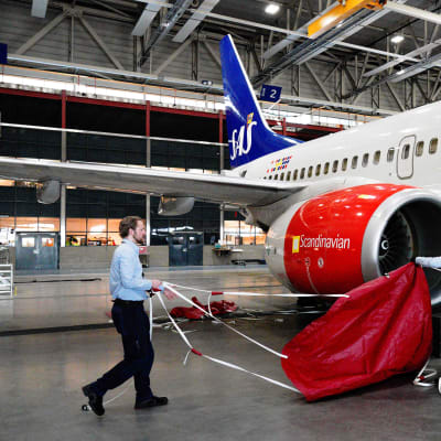 Lentomekaanikot asentavat suojia lentokoneen moottorin päälle lentokoneiden säilytyshallissa Oslossa.