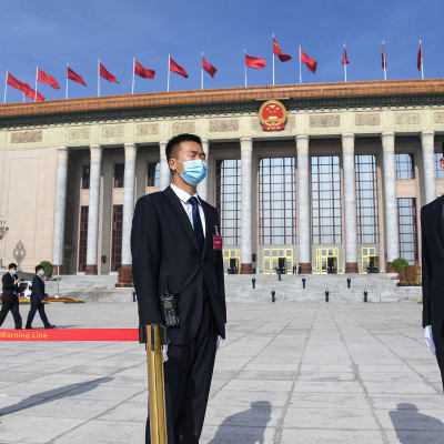 KAsvomaskeihin pukeutuneita turvamiehiä Kiinan kansantasavallan parlamenttitalon edustalla.