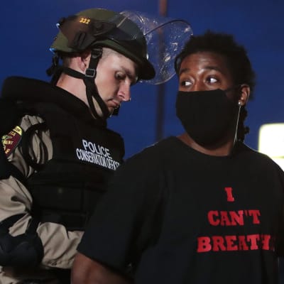 Kuvassa poliisi pidättää afroamerikkalaisen miehen.