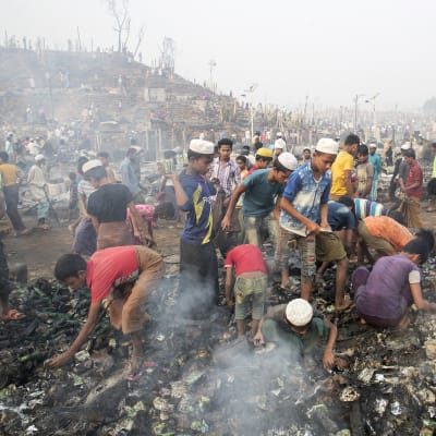 Pakolaiset etsivät omaisuuttaan tulipalon tuhon jälkeen.