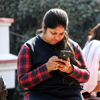 Intialaiset opiskelijat älypuhelimien kanssa internetissä.