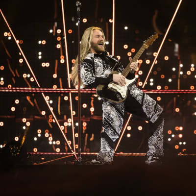 Mies esiinty lavalla kitaran kanssa.