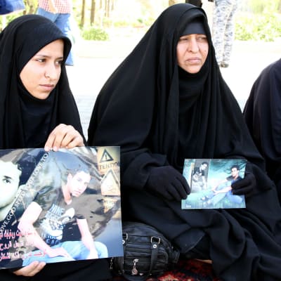 Irakiska kvinnor håller upp bilder på sina anhöriga som mördades i Speicher-massakern i juni 2014.