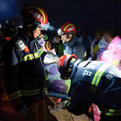Räddningsarbetare bär en person på bår efter att extremväder slagit till under ett ultramaraton i provinsen Gansu i Kina.