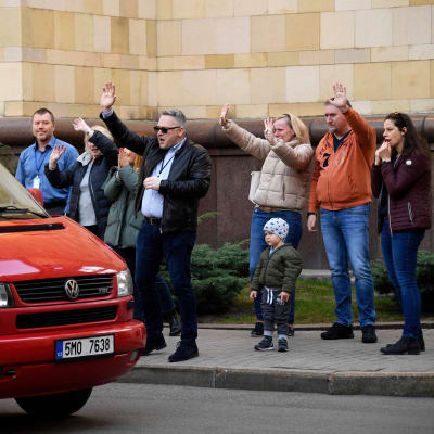 Tšekkiläiset diplomaatit vilkuttavat Moskovan suurlähetystön alueelta autolla poistuville.