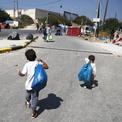 Kaksi lasta kävelee pakolaisleirissä Kreikassa.