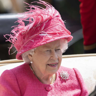 Kuningatar Elisabet vaaleanpunaisessa, sulin koristellussa hatussa.