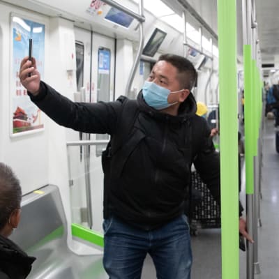 Passagerare i ett tunnelbanetåg i Wuhan, Kina. En av passagerarna tar en selfie. Bilden är tagen den 28 mars, samma dag som tunnelbanan öppnade igen efter paus på grund av coronavirusutbrottet i staden.