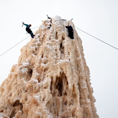 Jääkiipeilijä laskeutuu jäätornia alas köyden varassa.