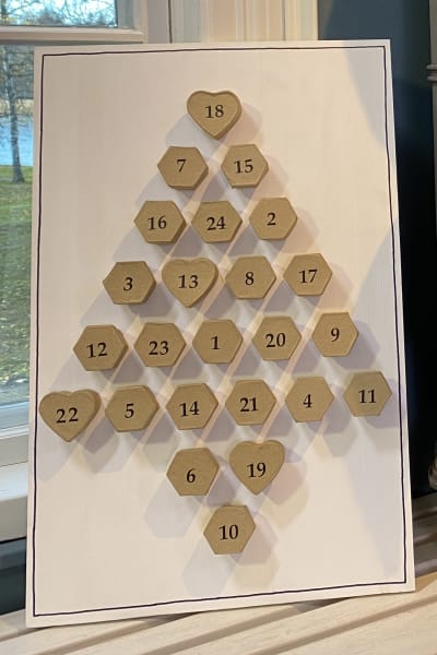 En adventskalender bredvid en leksaks gjutjärnskamin, båda handgjorda