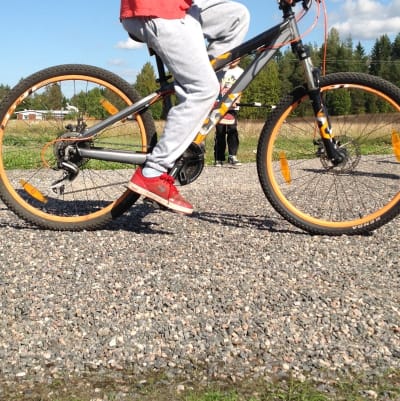 Barn som cyklar på grusväg