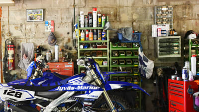 Två blå enduromotorcyklar inne i ett garage.