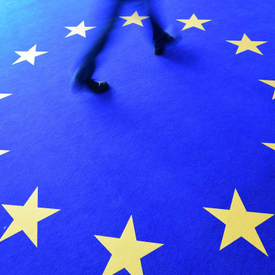 Mies kävelee matolla jossa on EU-lipun tähdet.