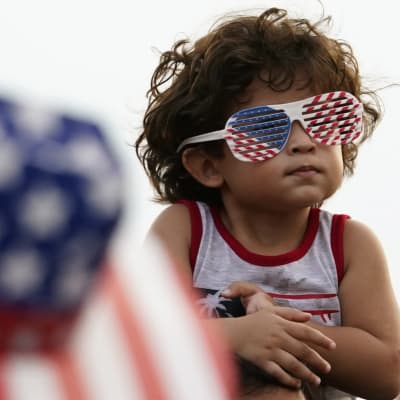 En liten pojke har glasögon på sig i USA:s flaggas färger.