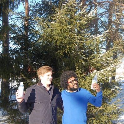 Grundarna till Lively Air Jouno Auri och Rathan Kumar står i en skog och håller i varsin flaska med luft från Finland.