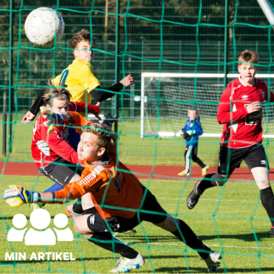 En målvakt försöker kasta sig efter en fotboll som går in i målet.