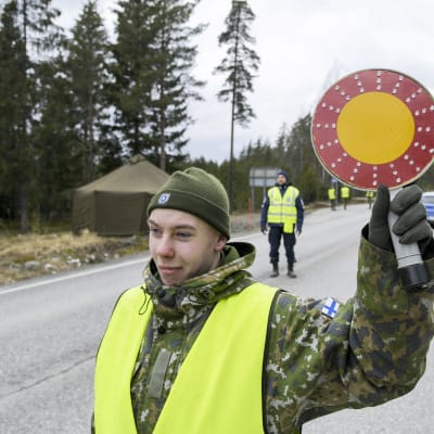 Varusmies ja poliiseja tarkastuspisteellä Uudenmaan ja Varsinais-Suomen rajalla kantatiellä 52 Raaseporissa. 