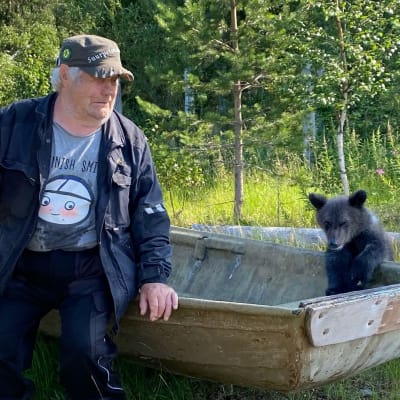 Aina karhunpentu ja Sulo Karjalainen tutustuvat vanhaan veneeseen Kuusamon suurpetokeskuksen rannassa.