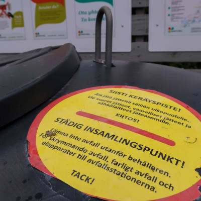 Bild av en påklistrad skylt på en avfallscontainer som uppmanar att inte lämna avfall utanför behållaren. 