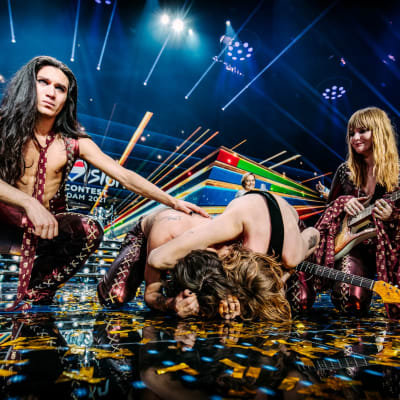 Ett band beståendes av fyra personer som står på en scen efter att ha vunnit Eurovision Song Contest. Två av dem ser ner i golvet.