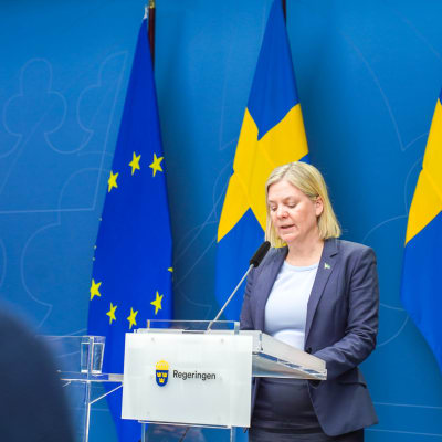 Magdalena Andersson håller tal framför Sveriges flagga.