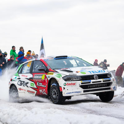 En rallybil susar fram på en vintrig väg.